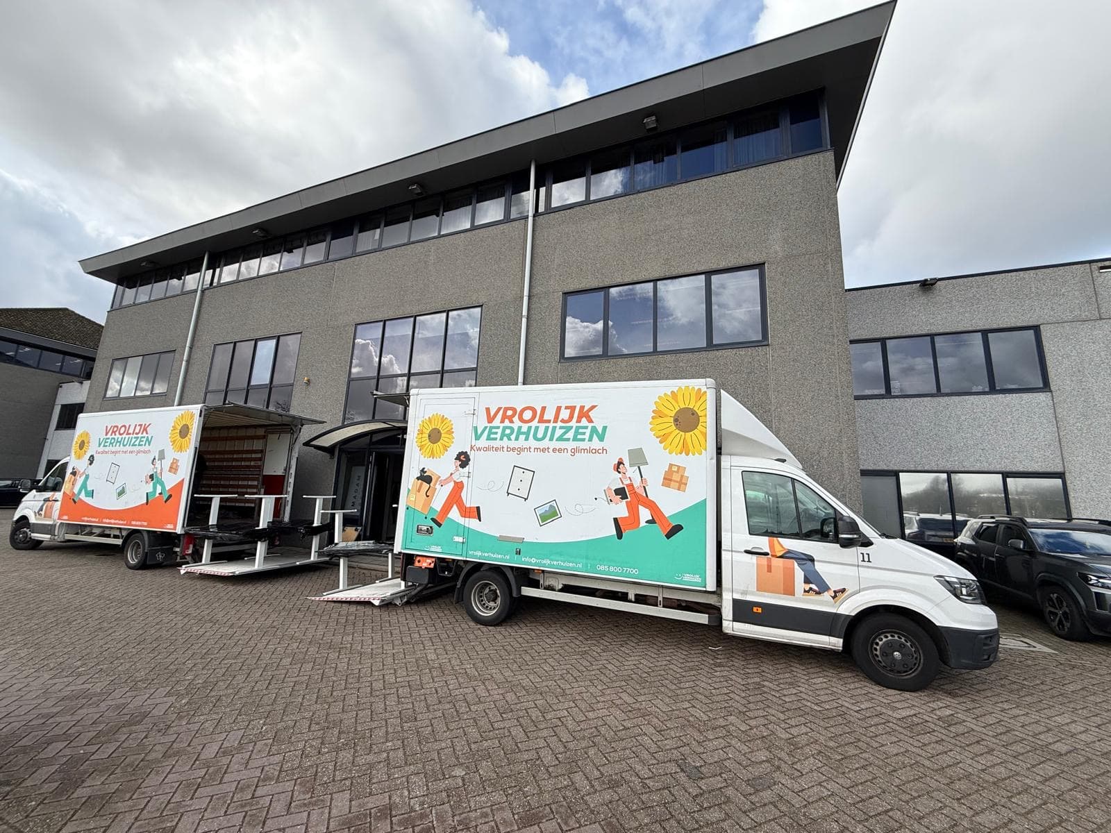 Meerdere Vrolijk Verhuizen bussen voor een bedrijfspand