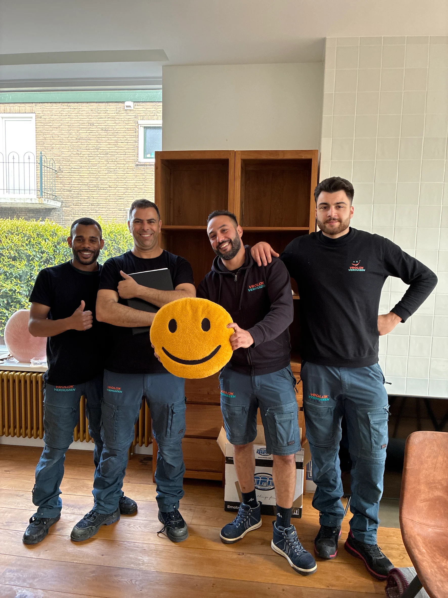Vier Vrolijk Verhuizen crewleden met de smiley die hun motto verbeeldt