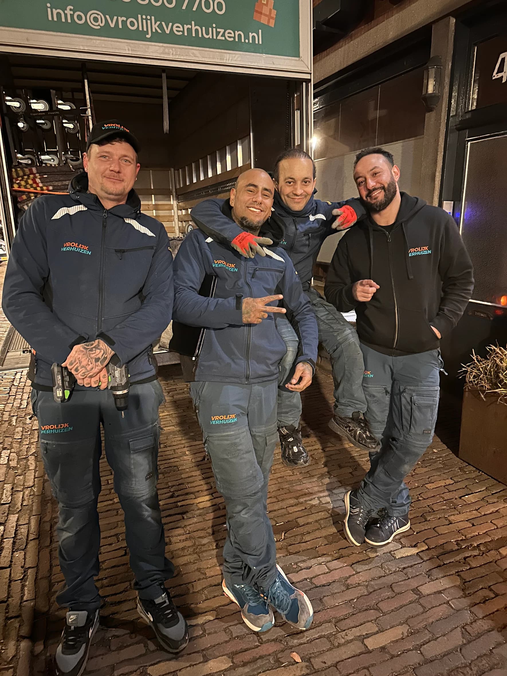 Vier verhuizers op de laadklep in de avond