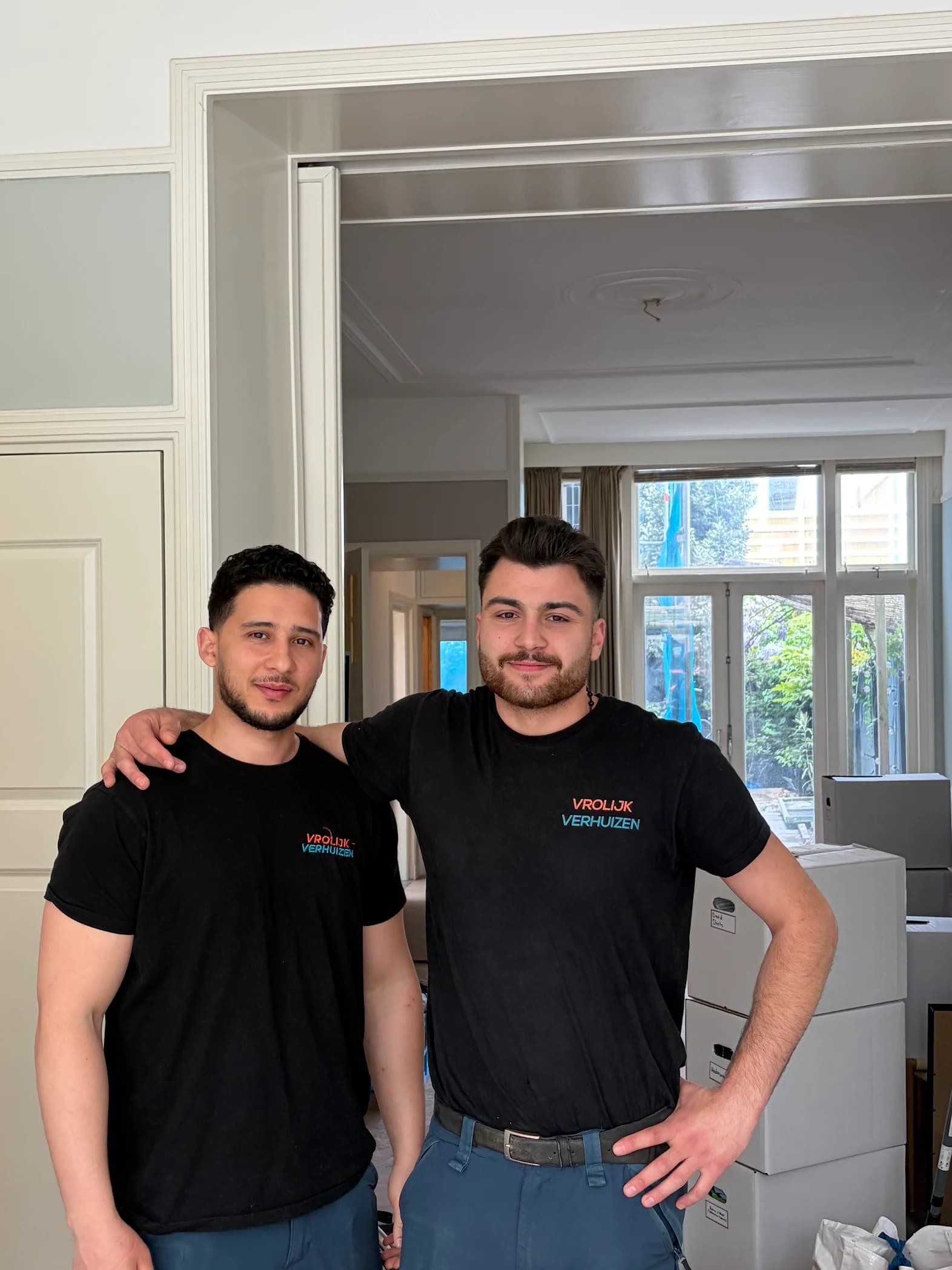 Twee crewleden met arm om de schouder tijdens een verhuizing