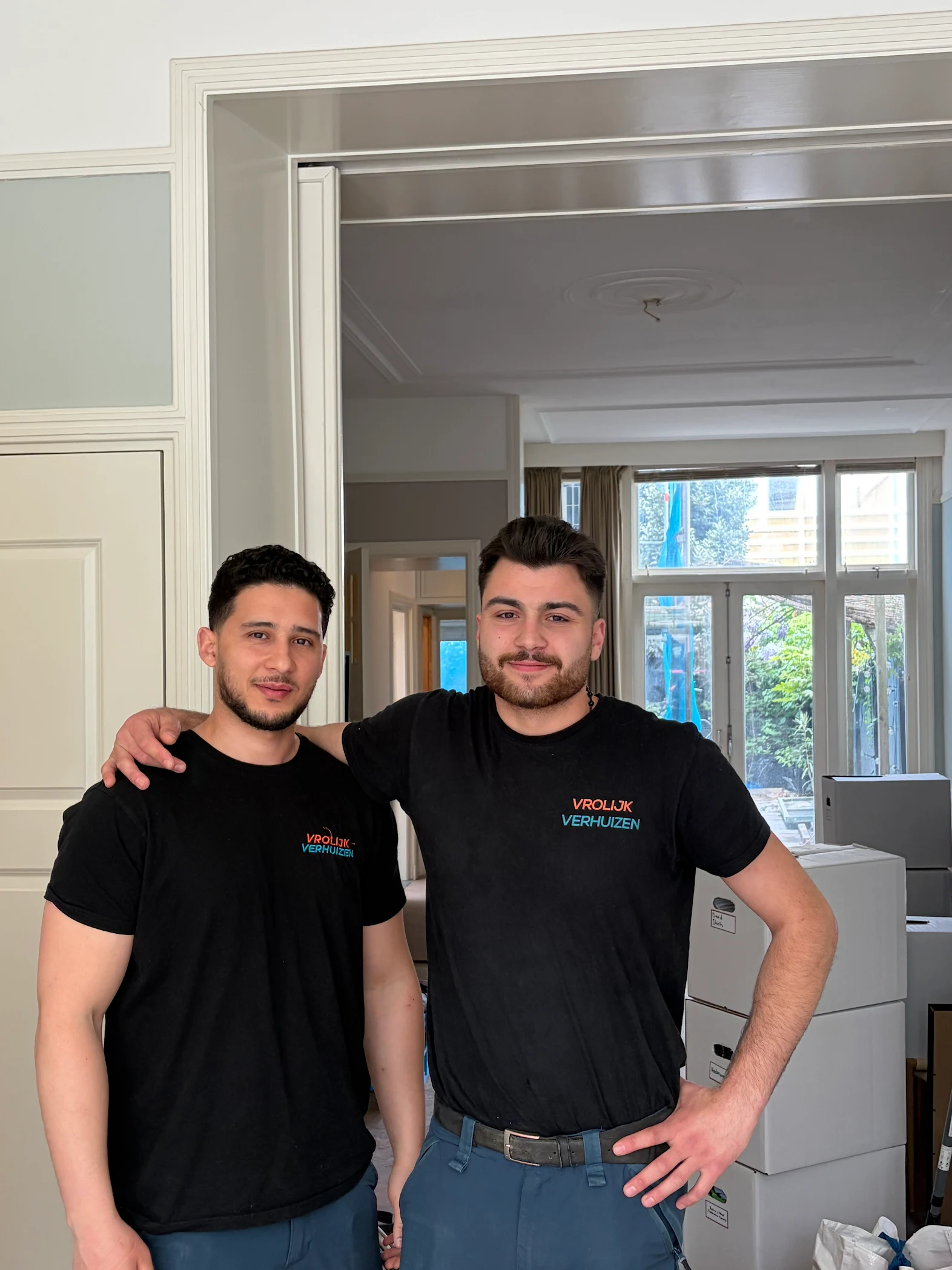 Twee Vrolijk Verhuizen crewleden met arm om de schouder tijdens een verhuizing