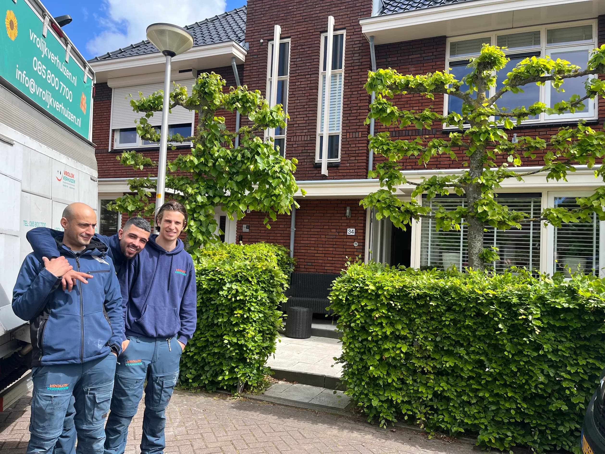 Drie crewleden voor een woonhuis met de bedrijfsbus
