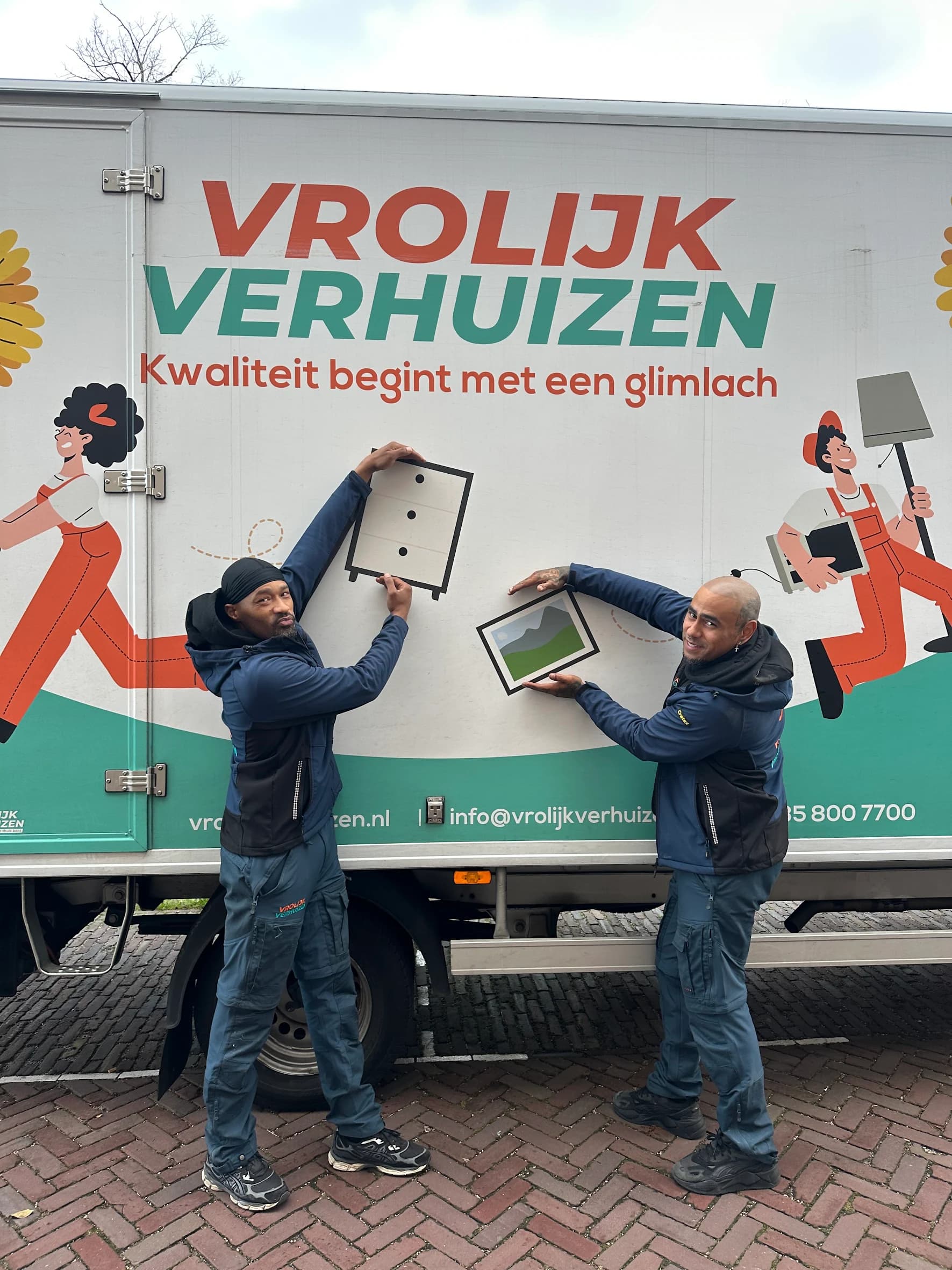 Crewleden poseren naast de Vrolijk Verhuizen bus