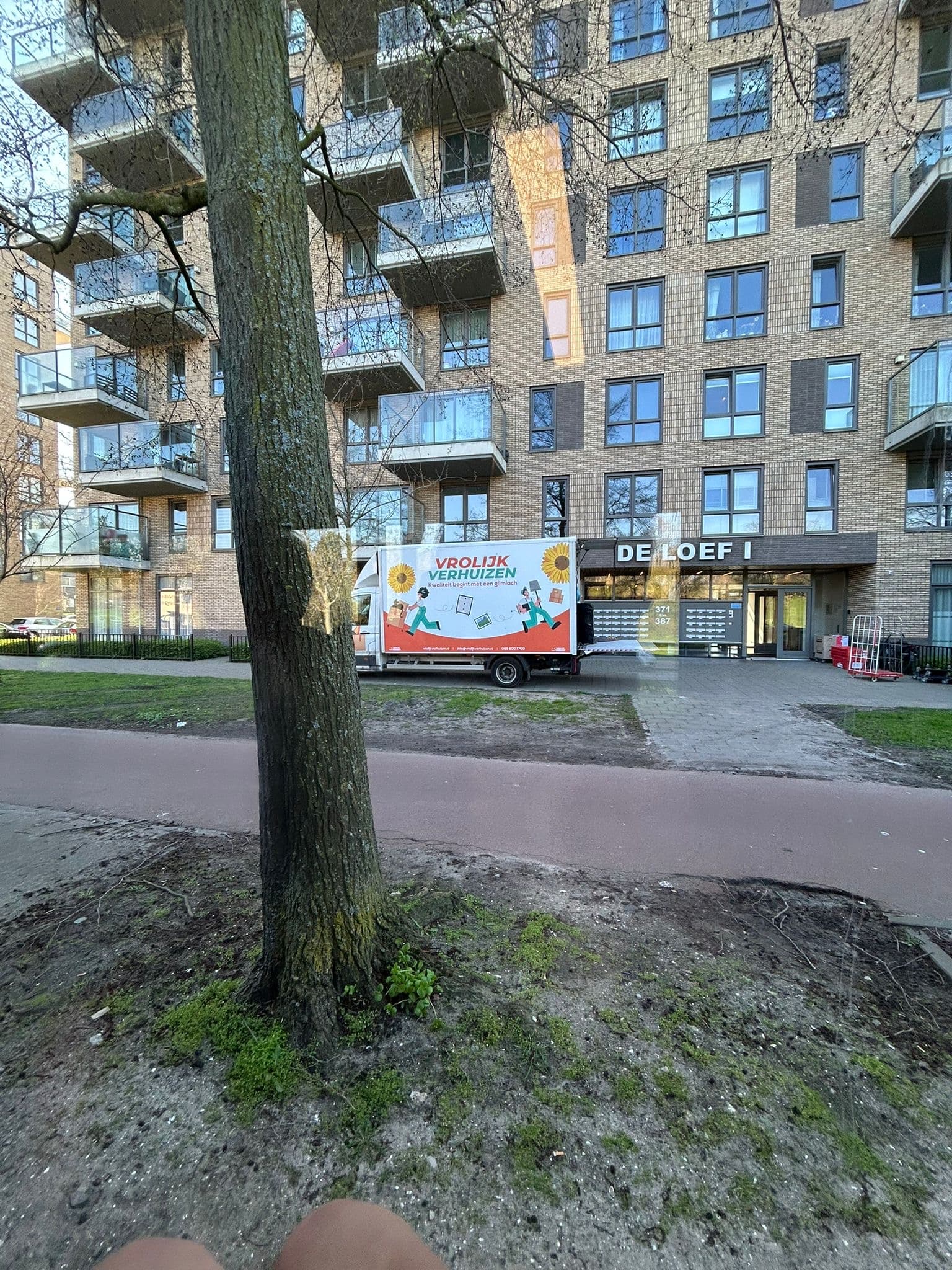 Vrolijk Verhuizen bus naast een kantoorpand bij een bedrijfsverhuizing